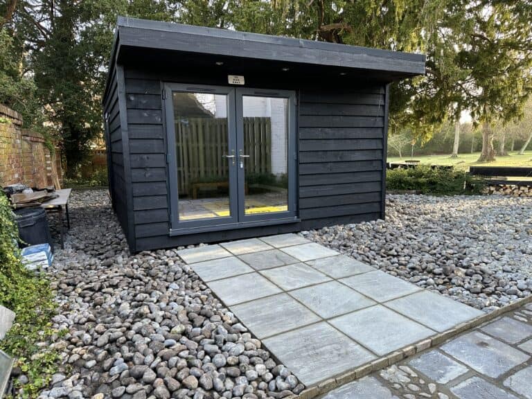 Modern black garden studio with glass doors in a residential garden